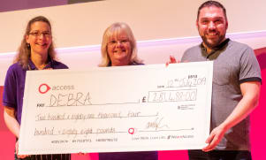 Image shows Dylans father handing over a large cheque to representatives from charity, DEBRA